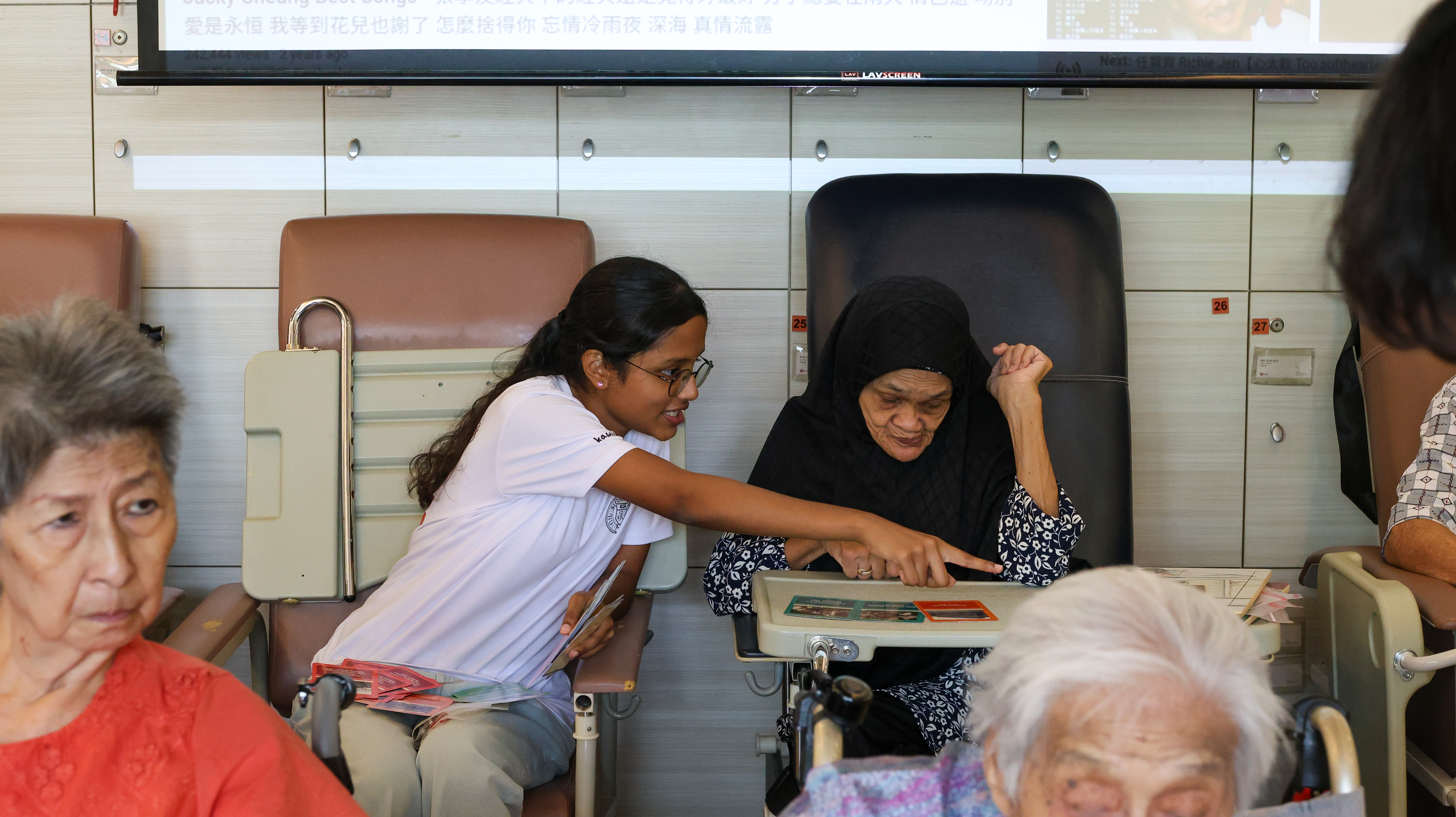 Volunteer teaches an elderly how to solve a puzzle